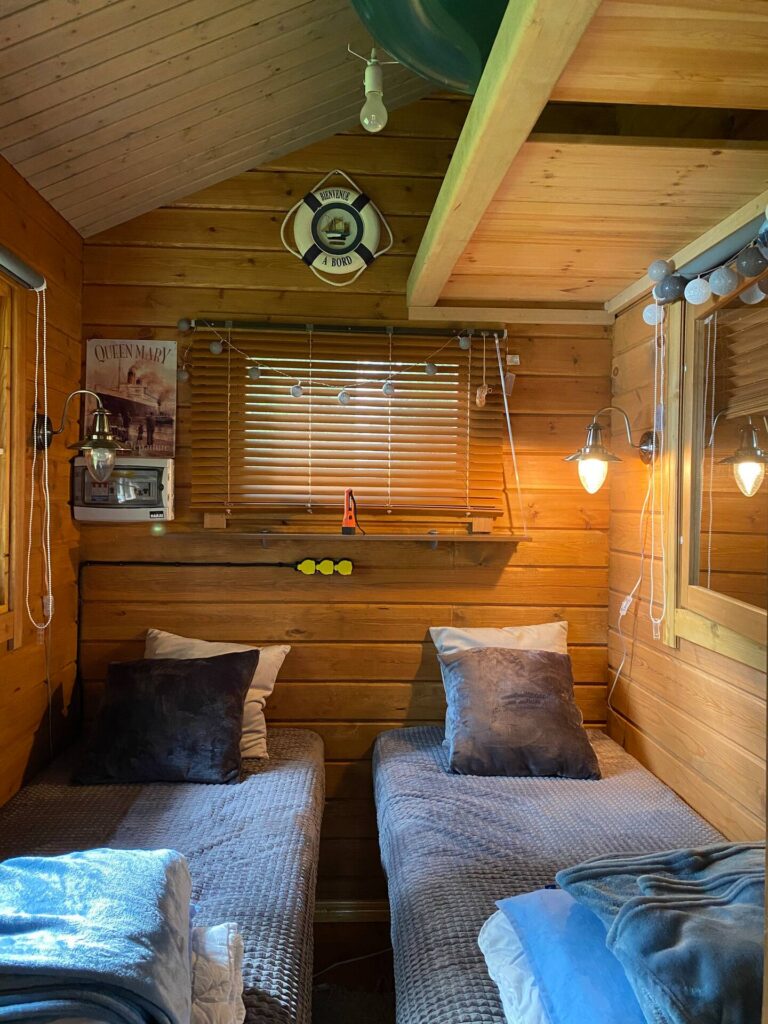 Kuva mökin makuutiloista. Kuvan huoneessa kaksi pedattua sänkyä.