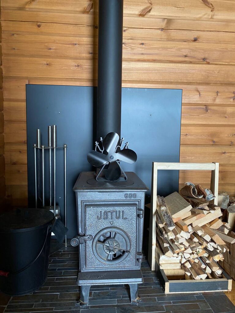 Kuva pienestä takasta, jonka vieressä halkoja.